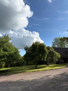 a house with a yard with trees in front of it at Le Cottage in Cambremer