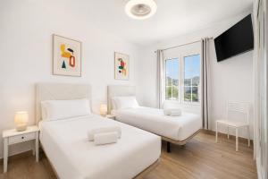 two beds in a white room with a window at Villa Yaiza Secret 3 in Yaiza +15 photos