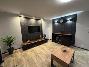 a living room with a television and a wooden table at Apartament W Cieniu Twierdzy in Kłodzko