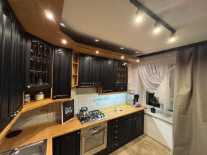 a kitchen with black cabinets and a sink and a window at Apartament W Cieniu Twierdzy in Kłodzko