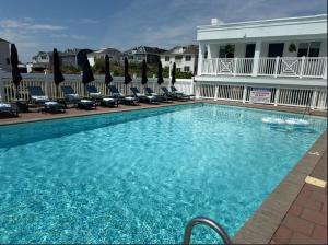 a large swimming pool with chairs and a building at Oceana By The Sea in Point Pleasant Beach