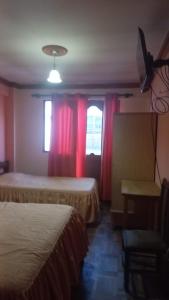 a room with two beds and a window with red curtains at Hostal Inca in Sucre