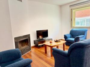 a living room with two blue chairs and a fireplace at NCHouse in Esposende