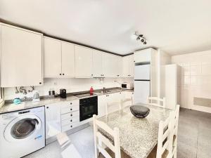 a kitchen with a washing machine and a table and chairs at NCHouse in Esposende