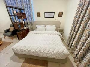 a bedroom with a white bed and a chair at Coco Caribbean Lodge in Accra