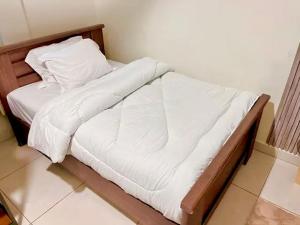 a bed with white sheets and pillows in a room at Coco Caribbean Lodge in Accra