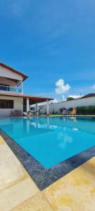 a large blue swimming pool in front of a house at Casapraiatracuá in Beberibe