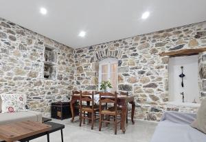 a dining room with a table and a stone wall at Summerstone Cottage in Aliveri +34 photos