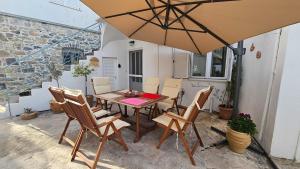 a patio with a table and chairs and an umbrella at Summerstone Cottage in Aliveri