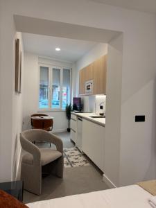 a kitchen with white cabinets and a chair and a table at La Encina Suites in Salamanca