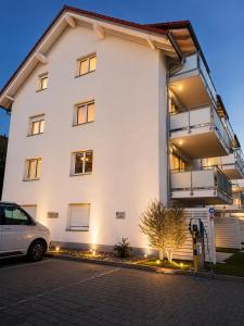 a white building with a car parked in front of it at Design Apartment 6 am Titisee mit Kamin, E-Ladestation, Balkon, Top Lage in Titisee