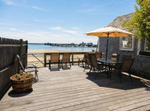 a wooden deck with a table and chairs and an umbrella at Waterfront Studio - Bay Views, Steps to Comm St in Provincetown