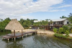 a dock with a bench and a straw umbrella at Luxury Waterfront 3bd Villa w Pool Dock in Maya Beach