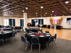 a banquet hall with black tables and chairs and a stage at Expedition Lodge Estes Park at Rocky Mtn National Park in Estes Park