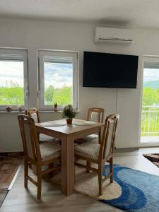 a dining room with a table and chairs and a television at Apartman Riverside Ripač in Ripač