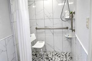 a bathroom with a shower with a stool in it at Days Inn by Wyndham Apple Valley Pigeon Forge/Sevierville in Pigeon Forge +28 photos
