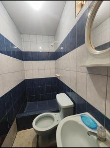 a blue and white bathroom with a toilet and a sink at Hostal Romances in Chimbote