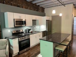 a kitchen with white cabinets and a counter top at Downtown Suite with Balcony in Syracuse +9 photos