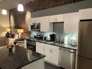 a kitchen with white cabinets and black counter tops at Downtown Suite with Balcony in Syracuse