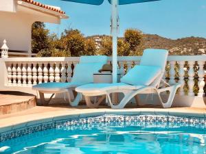 a pair of chairs and an umbrella next to a swimming pool at Luxury Casa da Fonte - Private Heated Salt Pool in Faro