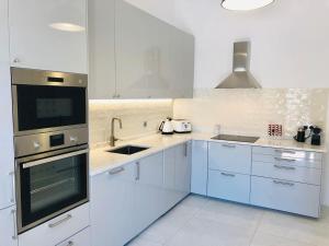 a kitchen with white cabinets and a stove top oven at Luxury Casa da Fonte - Private Heated Salt Pool in Faro
