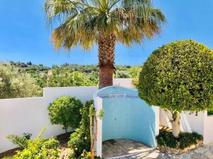 a palm tree next to a white fence with a palm tree at Luxury Casa da Fonte - Private Heated Salt Pool in Faro