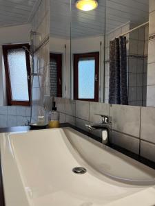 a large white tub in a bathroom with a mirror at Ferienwohnung Zum Rottweiler Städtle - Erdgeschosswohnung in Rottweil +9 photos
