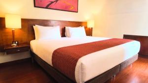 a large bed in a hotel room with two lamps at Hotel American Blessing in Bogotá