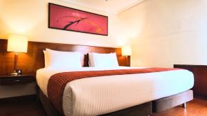 a hotel room with a large bed and a painting on the wall at Hotel American Blessing in Bogotá