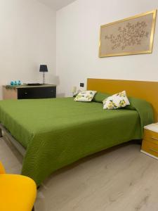 a bedroom with a green bed and a yellow chair at Casa Piazzetta in Saluzzo