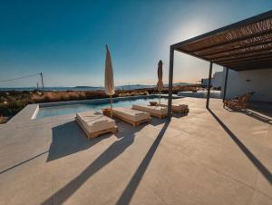 a pool with chaises and umbrellas on a patio at Faragas Hill Euphoria Villa in Angairiá