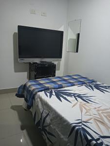 a bedroom with a flat screen tv and a bed at APARTAMENTOS Don GUILLE in Santa Rosa de Cabal