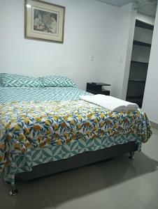 a bed with a comforter on it in a bedroom at APARTAMENTOS Don GUILLE in Santa Rosa de Cabal