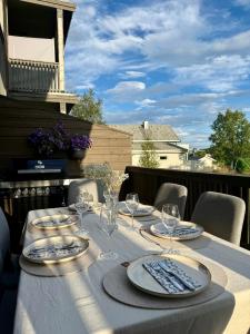 a table with plates and wine glasses on a balcony at Lux Apartment Gravdal in Gravdal