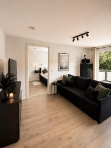 a living room with a black couch and a bedroom at Design Apartment 5 am Titisee mit Kamin, E-Ladestation, Balkon, Top Lage in Titisee-Neustadt