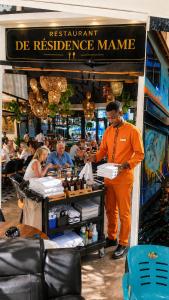 a man in an orange suit standing in front of a restaurant with a table at RÉSIDENCE MAME DIARRA kl in Kaolack +61 photos