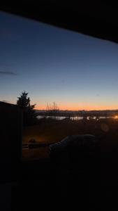 a view of a sunset from a window with a car at Ocean View Guesthouse in Borgarnes