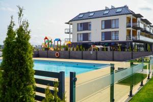 a building with a swimming pool and a playground at Przystań Apartamenty Sarbinowo in Sarbinowo