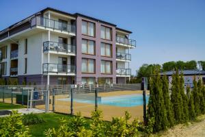an apartment building with a swimming pool in front of it at Przystań Apartamenty Sarbinowo in Sarbinowo