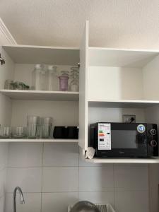 a kitchen with white cabinets with a microwave in it at Plaza Cervante II in Santiago
