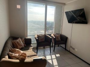 a living room with a couch and chairs and a window at Plaza Cervante II in Santiago