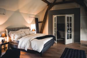 a bedroom with a king sized bed and a bathroom at Domein Fonteinhof B&B in Borgloon