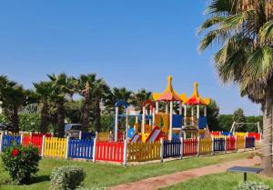 a colorful playground in a park with a fence at Bel appartement Savannah Beach in Sidi Rahal