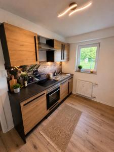 a kitchen with wooden cabinets and a sink and a window at Moderne Terrassenwohnung mit privatem Eingang in Ennepetal
