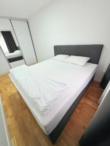 a bed with white sheets and pillows in a room at Sky apartment in Sarajevo