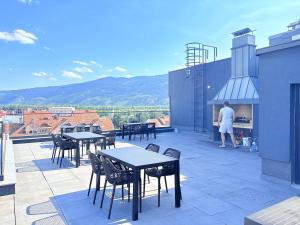 a person standing on a rooftop with tables and chairs at Sky apartment in Sarajevo