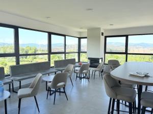 a dining room with tables and chairs and windows at Sky apartment in Sarajevo