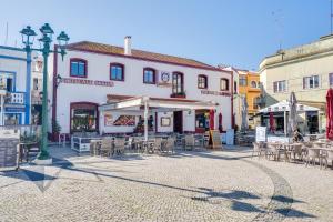 a street with tables and chairs in front of a building at Suites By The River in Ferragudo
