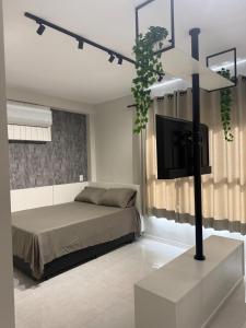 a bedroom with a bed and a flat screen tv at Studio 44 Luxo Design Com Closet, Office e Ar in Mogi das Cruzes