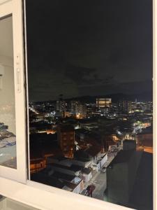 a view of a city at night from a window at Studio 44 Luxo Design Com Closet, Office e Ar in Mogi das Cruzes